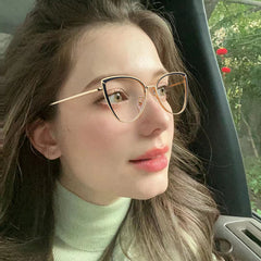Woman wearing cat-eye glasses inside a vehicle with blurred background